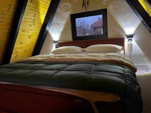 a bedroom with a bed with a tv on the wall at Green Zone - Vikendica in Dubrave Gornje