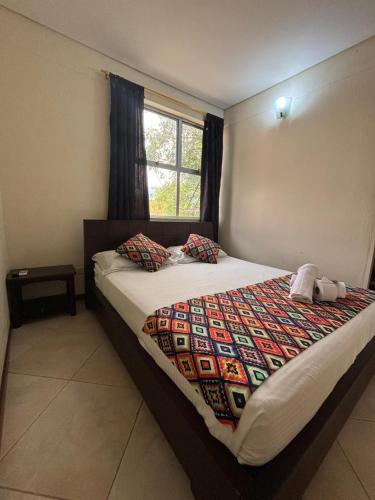 a bedroom with a bed with a comforter and a window at Hotel Tierra Santa Santa Fe de Antioquia in Santa Fe de Antioquia