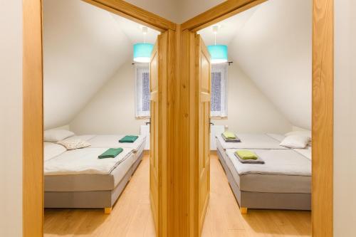 Kaszëbsko Nórcëk 8-10 osób 4 sypialnie jezioro las park linowy łowisko wędkarskie في Załakowo: سريرين توأم في غرفة بها نافذتين