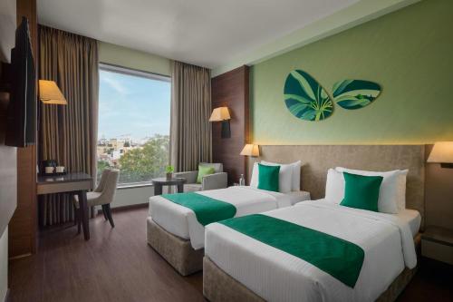 Una habitación de hotel con dos camas, un escritorio y una ventana. en The Fern, Vadodara, Series by Marriott, en Vadodara