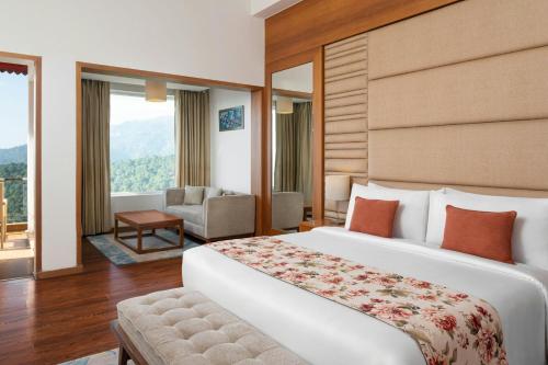 um quarto de hotel com uma cama grande e uma cadeira em The Fern Surya Resort Kasauli Hills, Dharampur, Series by Marriott em Kasauli