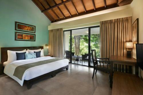 a bedroom with a large bed and a desk and a desk at The Fern Samali Resort Dapoli, Series by Marriott in Dapoli
