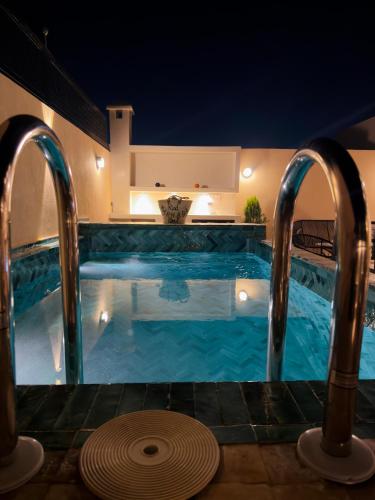 a swimming pool at night with two faucets at Riad Marhaba in Marrakesh