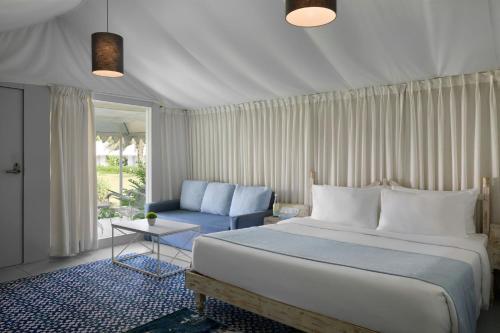 The Fern Seaside Luxurious Tent Resort Daman, Series by Marriott في دامان: غرفة نوم بها سرير كبير وكرسي أزرق