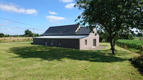 a black and white house with a tree in a field at Gîte de l'hamelinaie in Montanel