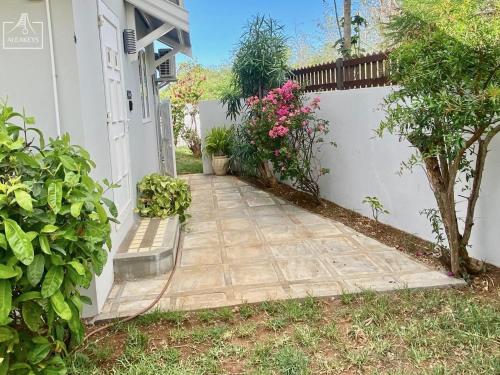 Villa Le Coin - T2 moderne climatisé avec Wi-Fi في Midlands Station: ممشى امام بيت به زهور