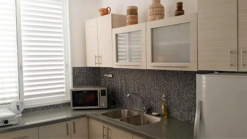 a kitchen with a sink and a microwave at Marina's Home By The Sea in Bat Yam