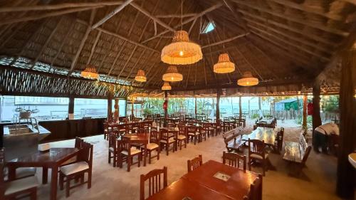 a dining room with tables and chairs and chandeliers at Hotel Fisherman lodge, cuarto base triple in Punta Allen