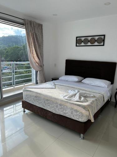 a bed in a bedroom with a large window at Apartamento exclusivo con Piscina y Vista panoramica, Anapoima Centro in Anapoima