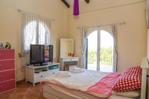 a bedroom with a bed with a tv and a window at Villa Sakura in Kyrenia