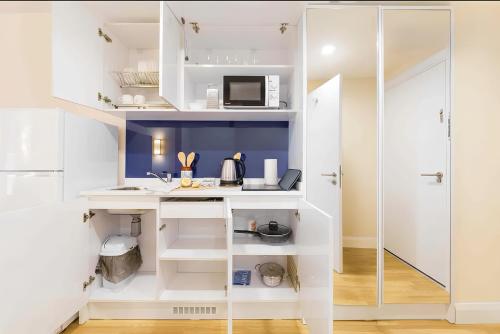 PANORAMA sea VIEW suite APARTMENTS في باتومي: مطبخ بخزائن بيضاء وطاولة عمل