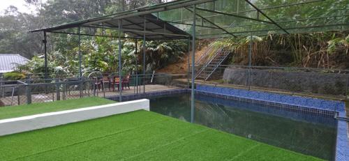 ein Haus mit einem Pool mit grünem Gras in der Unterkunft Hill valley farm resort in Viripara