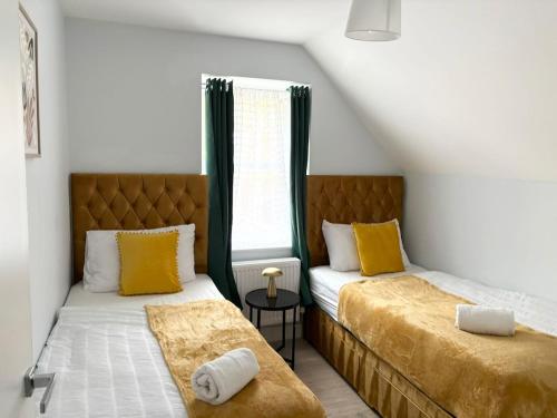 1 dormitorio con 2 camas con almohadas amarillas y ventana en Elegant Retreat 6 Mins Drive from Ferry With Free Parking, en Dover