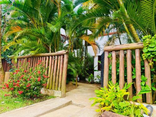 Una valla de madera con algunas flores y palmeras. en Pousada Casa Palo, en Itacaré