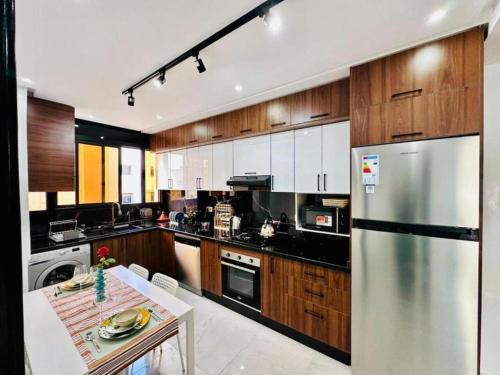 Una cocina con gabinetes de madera y un refrigerador de acero inoxidable. en Elegant 3BR Stay 5min to Hay Riad, en Temara