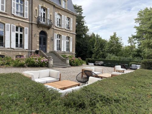 a garden with couches and tables in front of a building at Domaine des Monts de la Baie in Mareuil-Caubert