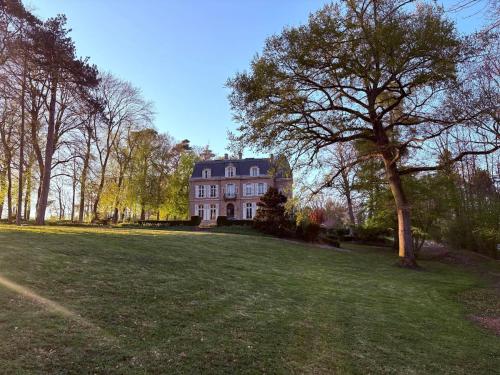 a large house with a tree in the middle of a field at Domaine des Monts de la Baie in Mareuil-Caubert