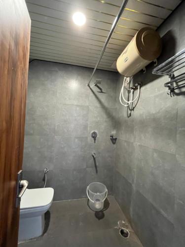 ein Badezimmer mit Toilette und Licht an der Wand in der Unterkunft Keshav Hotel Haridwar in Haridwar