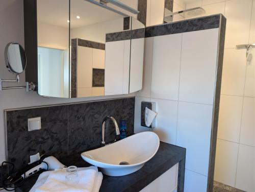 Landhaus Hotel Müller في Ringheim: حمام مزود بحوض ومِرآة