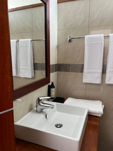 a bathroom with a sink and a mirror and towels at Hotel Dunas Boavista in Sal Rei