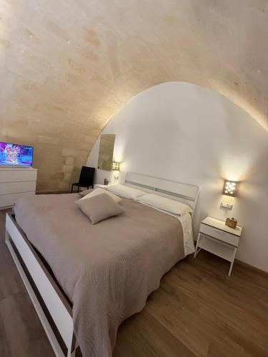 a bedroom with a large bed and a tv at Le note dei Sassi Holiday Home in Matera