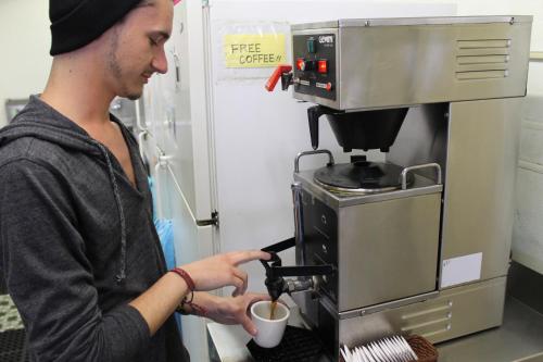 a man is pouring coffee into a coffee machine at Venice Beach Hostel in Los Angeles