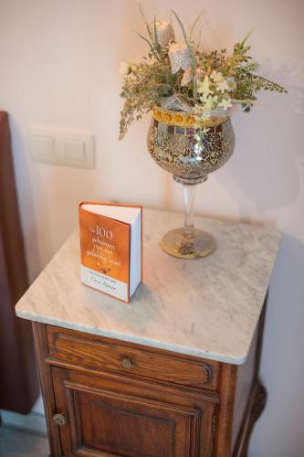 a table with a vase of flowers and a box at B&B Casa Roman & Vakantiewoning voor 1 pers tot max 32 personen in Zonhoven