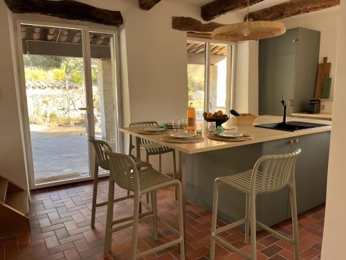 eine Küche mit einer Insel mit Stühlen und einem Tisch in der Unterkunft Mas En Pierre in Vercoiran