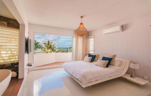 Villa MAEVA is your perfect beachfront escape في Roches Noires: غرفة نوم بها سرير ونافذة كبيرة