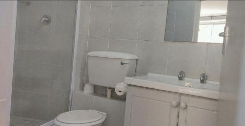a white bathroom with a toilet and a sink at SolSands Hotel & Self-Catering in Durban