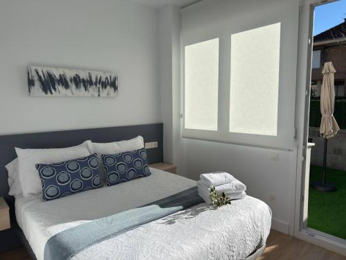 Alojamientos Dima Costa في لاريدو: غرفة نوم مع سرير ووسائد زرقاء ونافذة