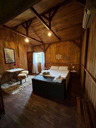 a bedroom with a bed in a wooden room at Pousada Quintal Verde in Guabiruba