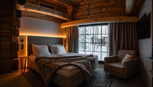 a bedroom with a bed and a chair and a window at Vaattunki Wilderness Resort in Rovaniemi