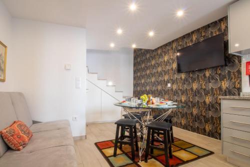 a living room with a table and a tv on a wall at Alto da Lapa House w Parking by LovelyStay in Porto
