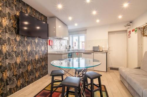 a kitchen and living room with a glass table and stools at Alto da Lapa House w Parking by LovelyStay in Porto