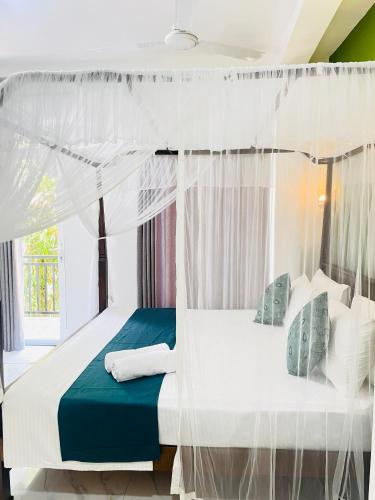 a bedroom with a white bed with a canopy at Kingsman Villa in Mirissa