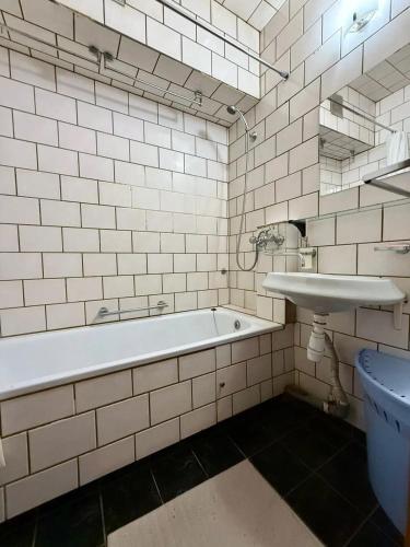 a white tiled bathroom with a tub and a sink at Apartmány Cestovatele in Jáma František