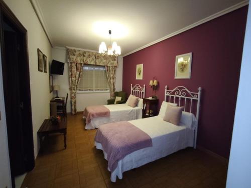 a bedroom with two beds and a red wall at Hostal Juan in Rosal