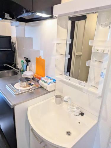 ein weißes Badezimmer mit Waschbecken und Spiegel in der Unterkunft Laundry Design House 妙典駅6分 in Ichikawa