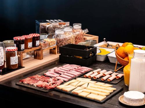 einen Tisch mit Fleisch, Käse und anderen Lebensmitteln in der Unterkunft Ibis Styles Lyon Villeurbanne Parc de la Tête d'Or in Villeurbanne