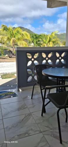 a patio with a table and chairs and palm trees at Ecofriendly Apartment in Gated Residence in Saint Martin