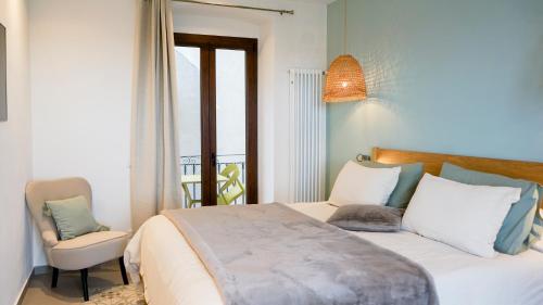 a bedroom with a bed with a chair and a window at Palazzo Cettina Sul Mare in Cefalù