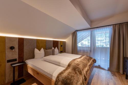 a bedroom with a large bed and a large window at Hotel Garni Mirabell in Ischgl