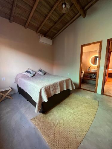 a bedroom with a bed with a rug and a mirror at Casa Beira rio Caraíva in Porto Seguro