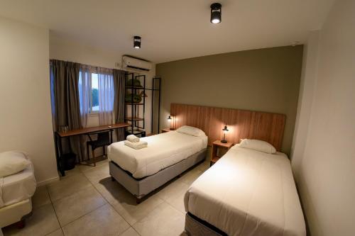 a hotel room with two beds and a desk at Casa Be Suites in Rosario