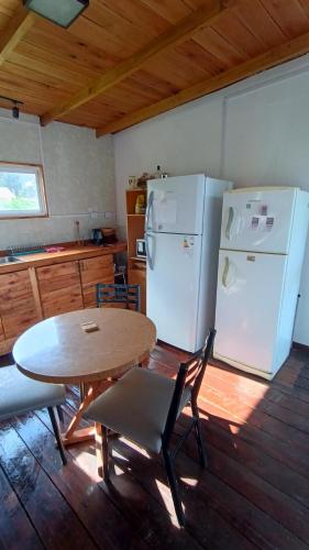 Una cocina con una mesa y un refrigerador blanco. en Kiya surf hostel, en Colonia Chapadmalal
