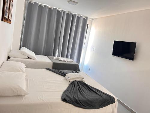 a hotel room with two beds and a flat screen tv at Villas do Porto Residence by La Playa in Porto De Galinhas
