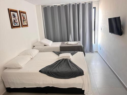 a room with two beds and a tv in it at Villas do Porto Residence by La Playa in Porto De Galinhas