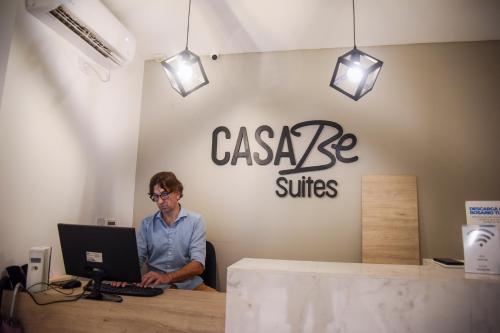 a man sitting at a desk with a laptop computer at Casa Be Suites in Rosario
