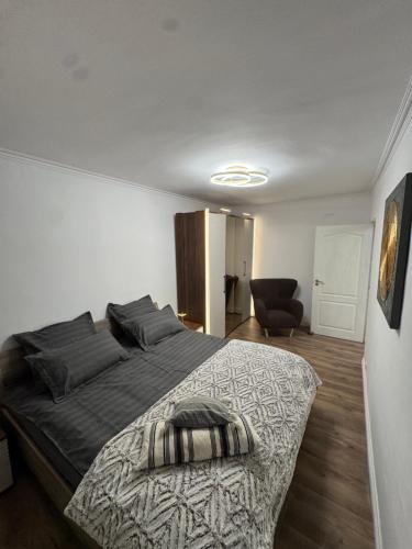 a bedroom with a large bed and a chair at Nest by Stefan in Drobeta-Turnu Severin